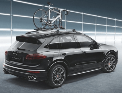 2026 Porsche Cayenne Turbo Electric prototype wrapped in neon test-livery under studio lighting with a wireless charging pad beneath it.