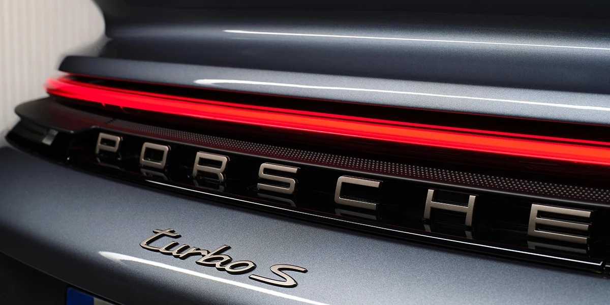 Porsche 911 Turbo S rear badge close-up with illuminated LED light strip and chrome “Turbo S” emblem.