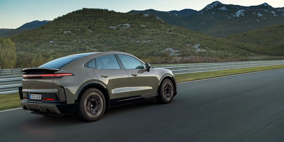 Side profile of a 2026 Porsche Cayenne Turbo Electric prototype in mountain terrain, highlighting its rugged stance and electric performance capability.