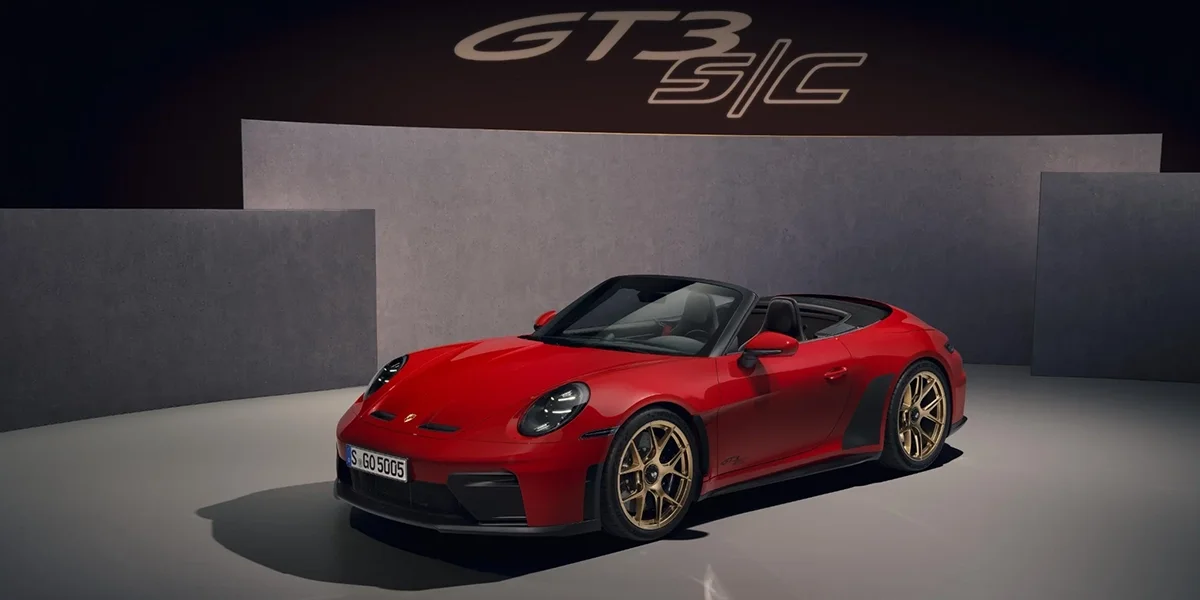 Red Porsche 911 GT3 RS Cabriolet with gold wheels displayed in studio from front angle.